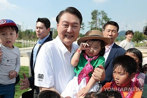 President Yoon Suk Yeol (C) poses with children during an event held for families with multiple children at Yongsan Children's Garden, near the presidential office, in Seoul on Aug. 26, 2023, in this photo provided by the office. (PHOTO NOT FOR SALE) (Yonhap)
