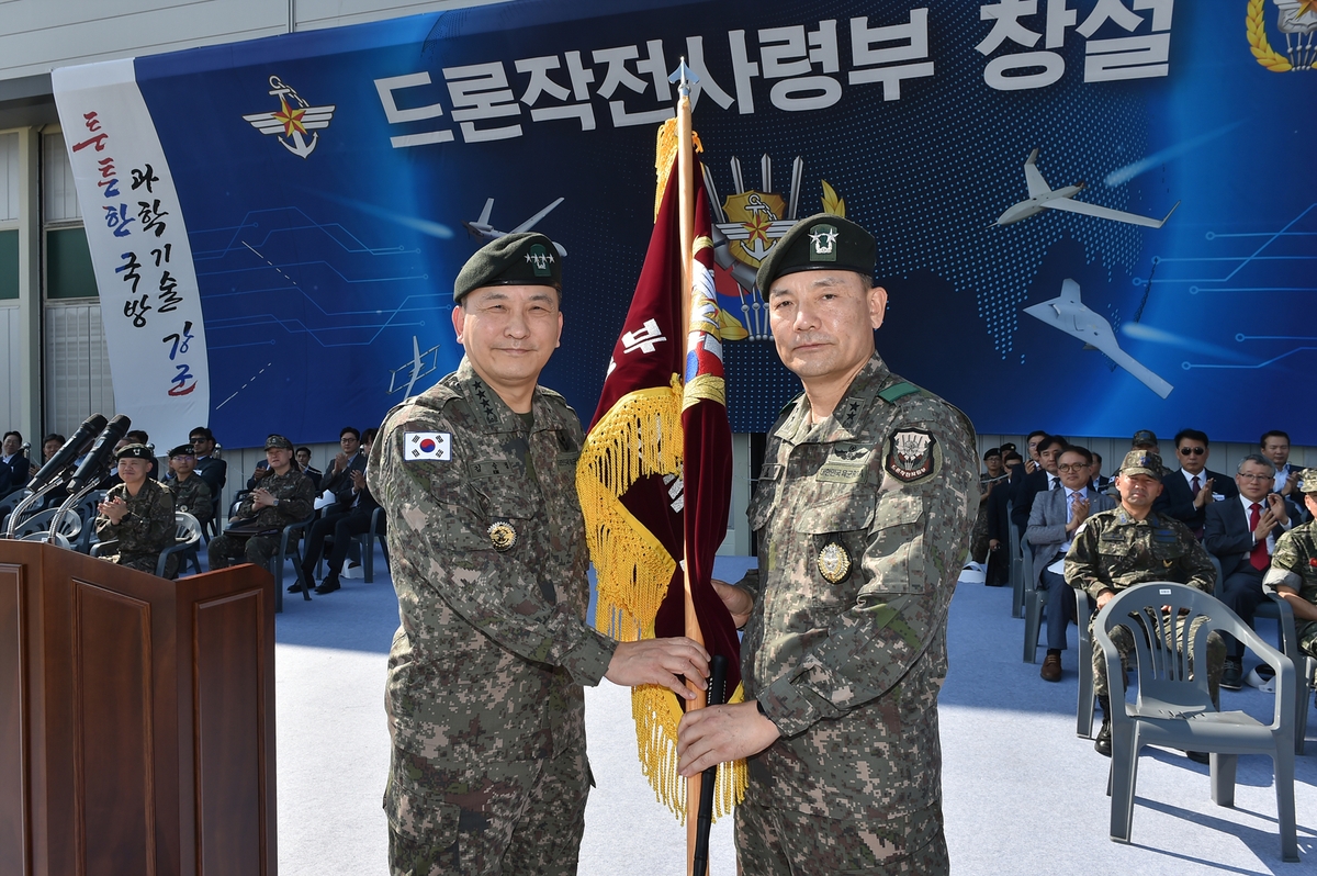 South Korea's Joint Chiefs of Staff (JCS) Chairman Gen. Kim Seung-kyum (L) presents the flag of the newly established Drone Operations Command to the unit's inaugural commander, Maj. Gen. Lee Bo-hyung, during the command's launch ceremony at an undisclosed area around Pocheon, 51 kilometers northeast of Seoul, on Sept. 1, 2023, in this photo provided by the JCS. (PHOTO NOT FOR SALE) (Yonhap)