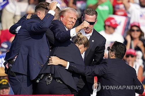 El expresidente Donald Trump es sacado a toda prisa del escenario en un evento de campaña en Butler, Pensilvania, el 13 de julio de 2024, después de un intento de asesinato, en esta fotografía difundida por Associated Press. (Yonhap)