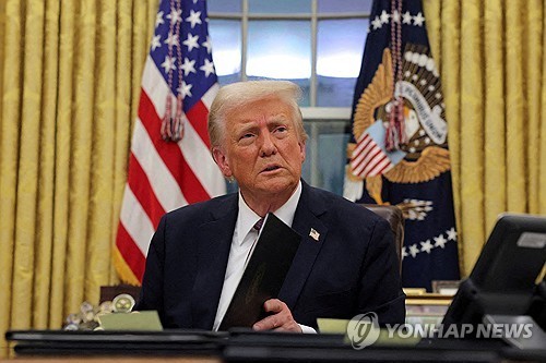 Esta foto de archivo, publicada por Reuters, muestra al presidente estadounidense Donald Trump firmando documentos en la Oficina Oval de la Casa Blanca en Washington el 20 de enero de 2025. (Yonhap)