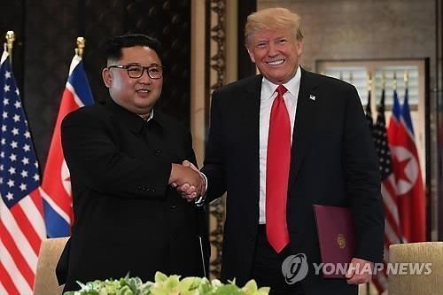 AFP'nin bu arşiv fotoğrafında, ABD Başkanı Donald Trump'ın (sağda) 12 Haziran 2018'de Singapur'daki Sentosa Adası'ndaki Capella Oteli'nde ortak bir bildiriyi imzalamasının ardından Kuzey Kore lideri Kim Jong-un ile el sıkıştığı görülüyor. (Yonhap)