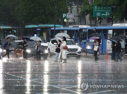 Pedestrians walk over a crosswalk with umbrellas at the Gwanghwamun intersection in central Seoul as heavier-than-expected rainfall hits the Seoul metropolitan area on May 16, 2025. (Yonhap)