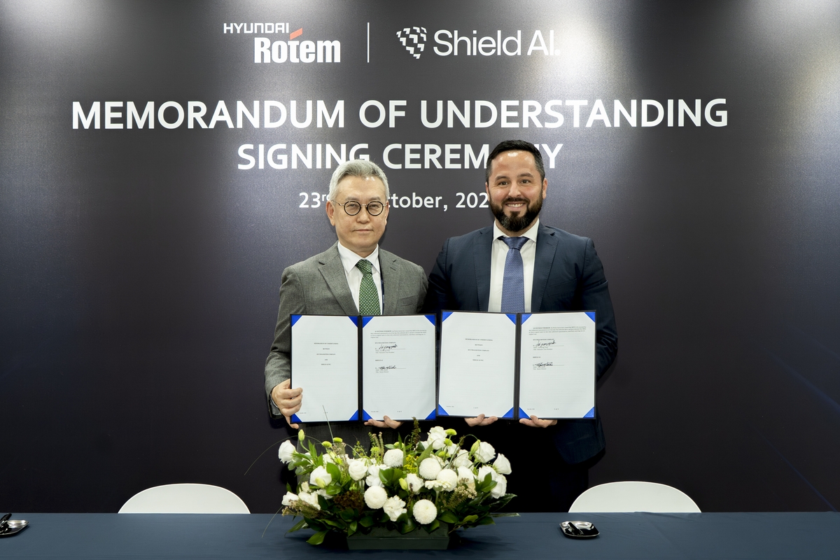 This photo, taken Oct. 24, 2025, and provided by Hyundai Rotem Co., shows the company's Executive Vice President Lee Jeong-yeob (L), head of the Defense Solution Business Division, and Mike Hanlin, Senior Director of International Strategy & Business Development at Shield AI, posing after signing a memorandum of understanding (MOU) on a partnership for artificial intelligence (AI)-based defense technologies during the 2025 Seoul International Aerospace & Defense Exhibition (ADEX) in Goyang, just northwest of Seoul. (PHOTO NOT FOR SALE) (Yonhap)