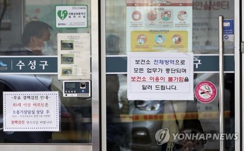 Un avis placardé sur la porte d'un centre de santé publique à Daegu, à 300 kilomètres au sud-est de Séoul, indique que le bâtiment sera temporairement fermé pour désinfection après que le 31e patient du pays a été testé positif au Covid-19 par le personnel médical de l'établissement, le 18 février 2020.