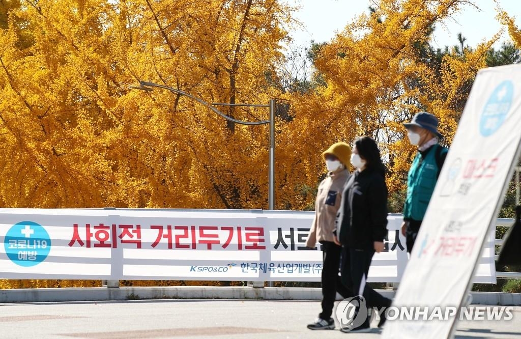 Des gens portant un masque marchent près d'un parc dans l'est de Séoul, le dimanche 8 novembre 2020.