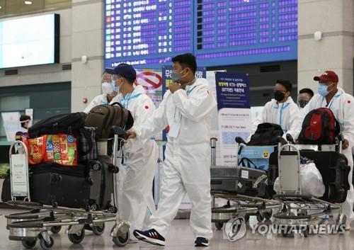 Des touristes étrangers en combinaison de protection entrent à l'aéroport international d'Incheon, à l'ouest de Séoul, le 2 décembre 2021, sur fond d'inquiétudes croissantes concernant la propagation du variant Omicron.