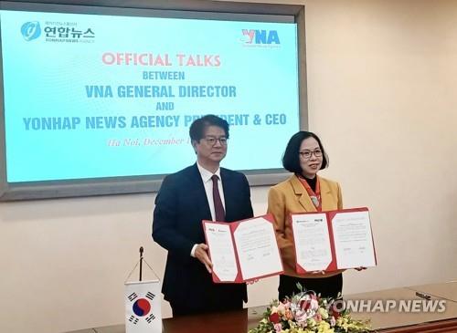 Le PDG de l'agence de presse Yonhap, Seong Ghi-hong et la directrice générale de l'Agence vietnamienne d'information (VNA), Vu Viet Trang, posent pour une séance photos le mercredi 14 décembre 2022 au siège de l'agence à Hanoï, après avoir signé un accord bilatéral pour lutter contre les fausses informations. 