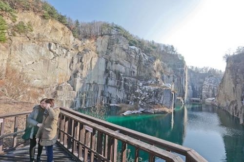 岩に囲まれた湖。台湾人観光客が写真を撮っている＝（聯合ニュース）
