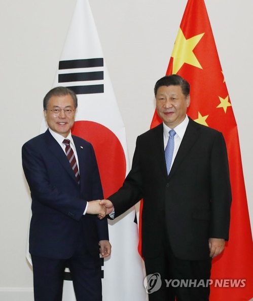 会談前に握手する文大統領（左）と習主席＝２７日、大阪（聯合ニュース）