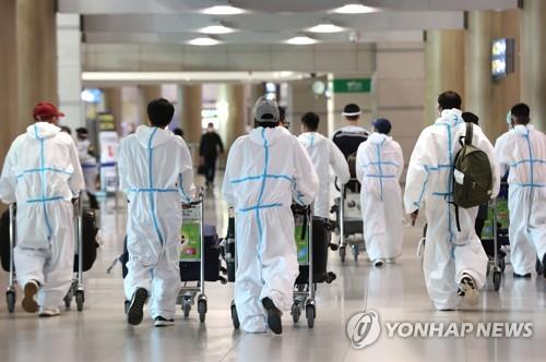仁川国際空港で、防護服を着て移動する外国人＝２日、仁川（聯合ニュース）