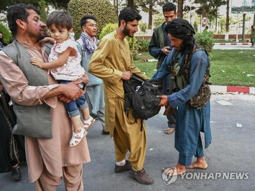 아프간 수도 카불의 국제공항에서 나오는 주민의 짐을 검사하는 탈레반 조직원(오른쪽). [AFP=연합뉴스]