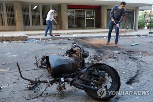 베이루트 총격전 와중에 불에 탄 오토바이 잔해와 거리를 청소하는 시민들. [로이터 연합뉴스 자료사진 재판매 및 DB 금지]