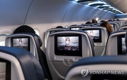 기내에서 마스크 착용을 강조하는 영상을 보고 있는 승객들