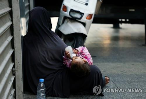 레바논 베이루트 시내에서 구걸하는 여성과 젖병을 문 아이. 