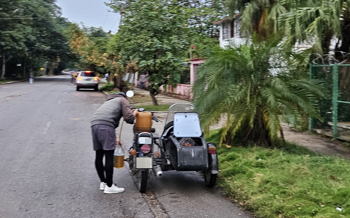따로 구입한 연료를 오토바이에 주유하는 쿠바 주민