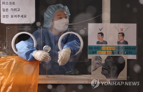 Una trabajadora sanitaria llama a una persona que espera para ser sometida a la prueba del nuevo coronavirus, el 19 de enero de 2022, en una clínica provisional, frente a la Estación de Seúl, en la capital surcoreana.
