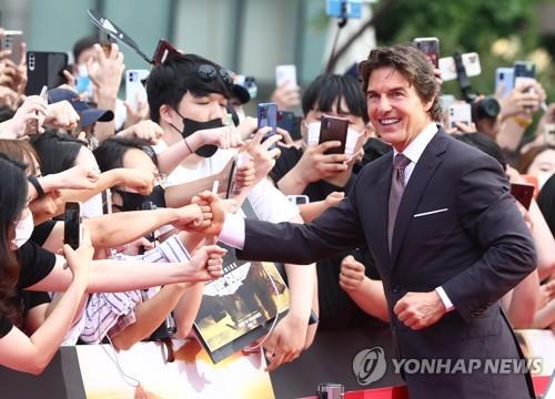 El actor estadounidense Tom Cruise (dcha.) saluda a sus fanes surcoreanos, el 19 de junio de 2022, durante un evento de alfombra roja para la película "Top Gun: Maverick", en la plaza de la Lotte World Tower, en Seúl.