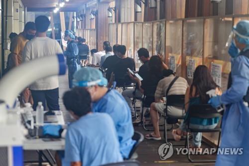 Las personas esperan sentadas para someterse a las pruebas del coronavirus, el 2 de agosto de 2022, en un centro de exámenes, en Seúl.