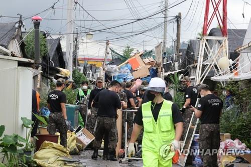 Unos soldados ayudan a desechar objetos arruinados por las inundaciones causadas por las fuertes lluvias, el 11 de agosto de 2022, en un vecindario en el distrito de Songpa, en Seúl. 