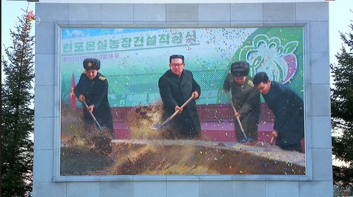 La foto, capturada, el 11 de octubre de 2022, de imágenes de la Estación Central de Televisión de Corea del Norte, muestra la instalación de un mural de mosaico del líder norcoreano, Kim Jong-un (segundo por la izda.), que lo muestra paleando tierra en una ceremonia para conmemorar el inicio de la construcción de la Granja de Invernadero de Ryonpho, en la provincia oriental de la nación, en febrero. (Uso exclusivo dentro de Corea del Sur. Prohibida su distribución parcial o total)