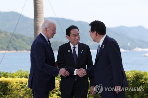 El presidente surcoreano, Yoon Suk Yeol (dcha.), saluda al presidente estadounidense, Joe Biden (izda.), y el primer ministro japonés, Fumio Kishida, antes de sostener una cumbre trilateral, el 21 de mayo de 2023, en Hiroshima, Japón, al margen de la cumbre del Grupo de los 7 (G-7). (Foto del cuerpo de prensa. Prohibida su reventa y archivo)