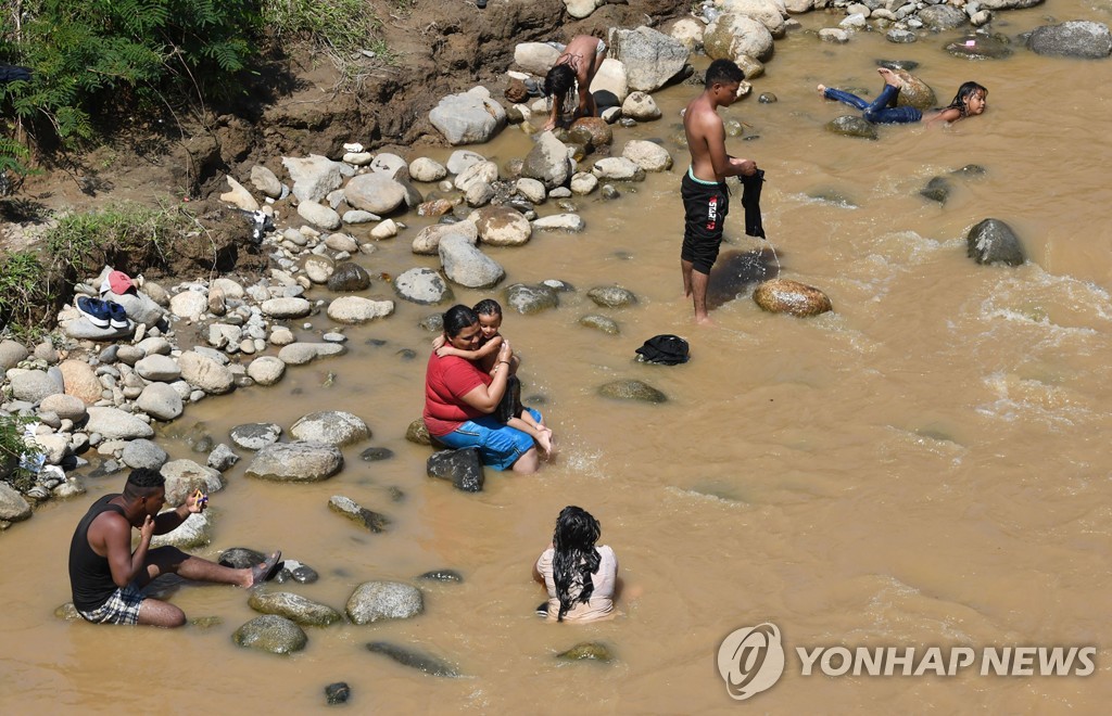 강에서 목욕과 빨래하는 이민자들