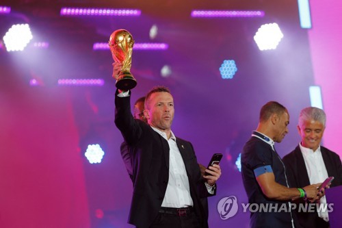 In this AFP photo, former German football star and World Cup ambassador Lothar Matthaus hoists the FIFA World Cup trophy during the Fan Festival event at Al Bidda Park in Doha on Nov. 19, 2022. (Yonhap)
