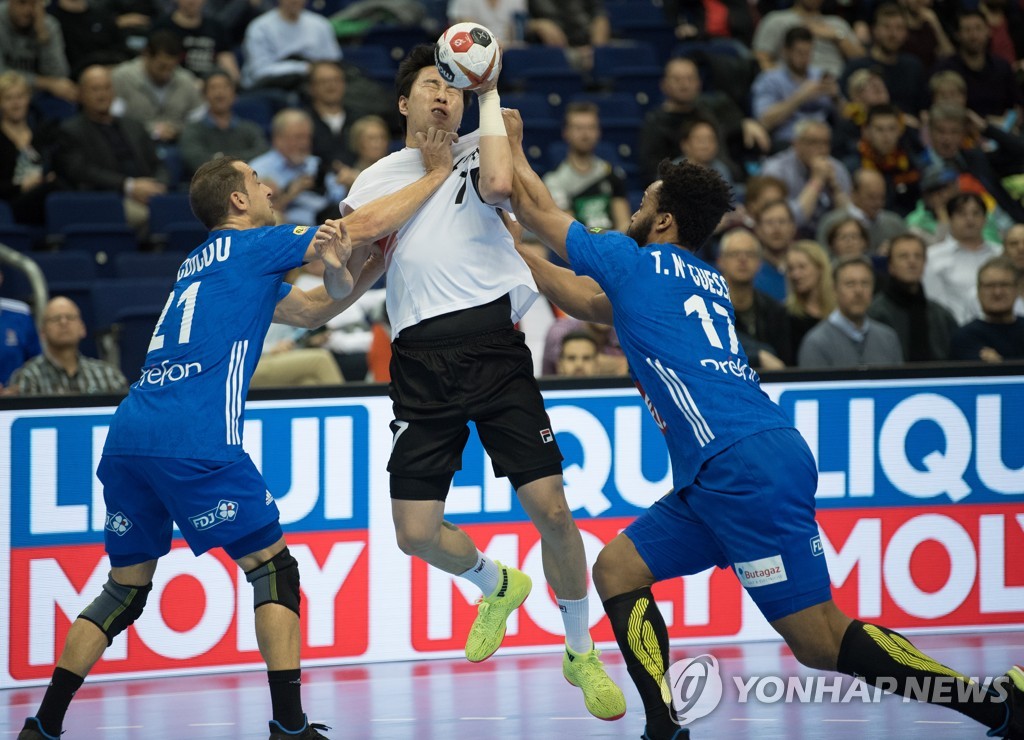 In this DPA photo, Jung Su-young of Korea (C) is held by Michael Guigou (L) and Timothey N'Guessan of France during the teams' Group A match at the International Handball Federation World Men's Handball Championship at Mercedes-Benz Arena in Berlin on Jan. 14, 2019. (Yonhap)