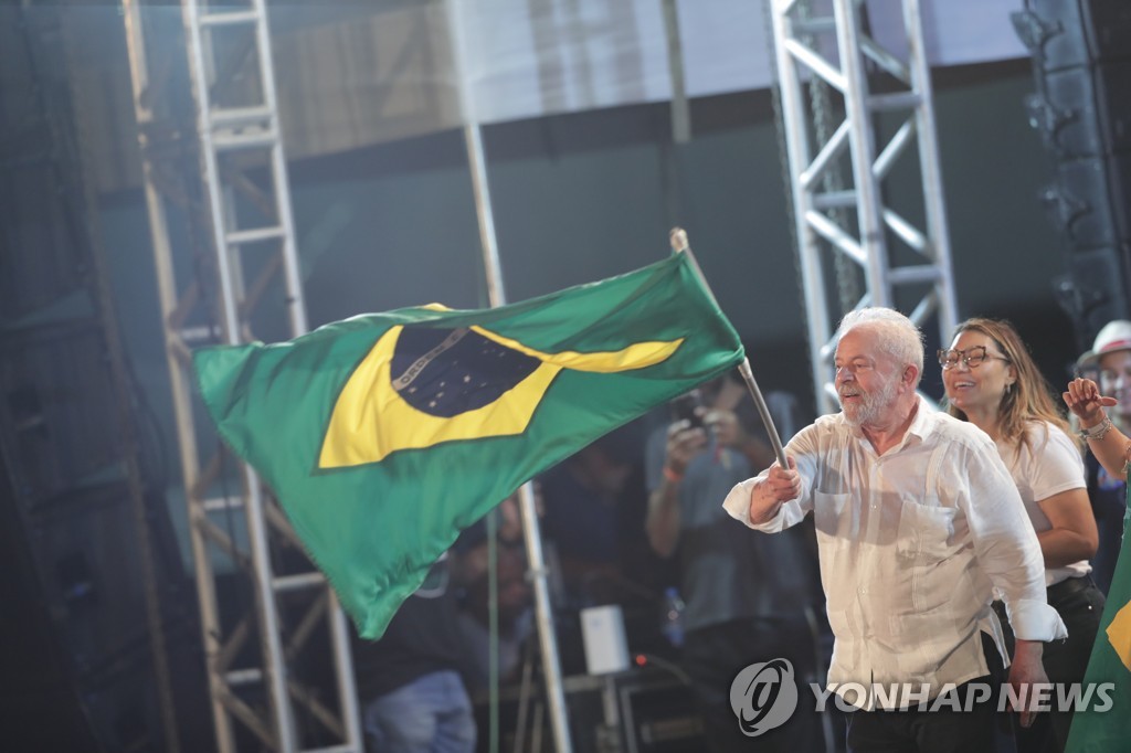 Lula eleito agita bandeira quadricolor do Brasil para se parabenizar pela vitória nas eleições presidenciais.