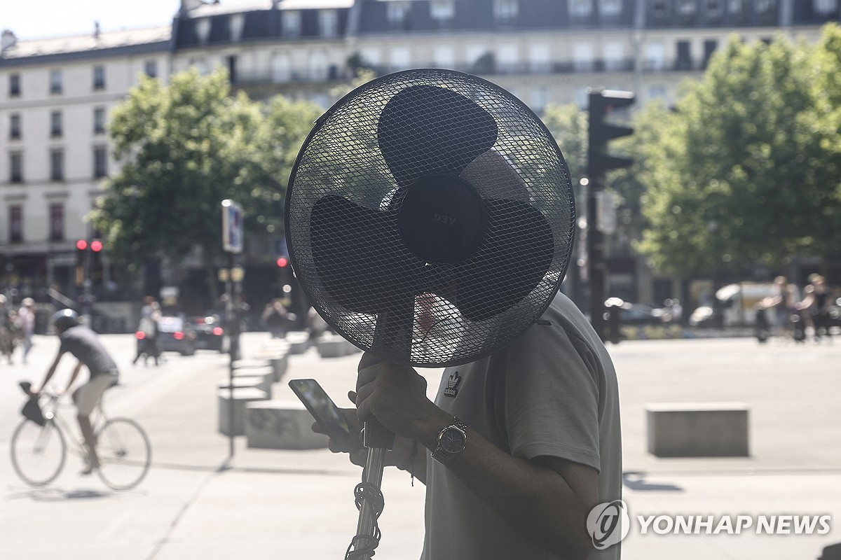 선풍기를 든 채 파리 시내를 걷는 남성