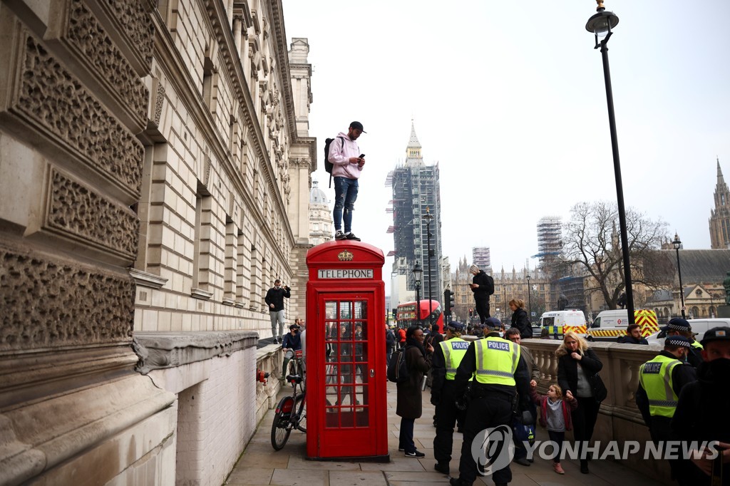봉쇄조치 반대 시위 도중 전화박스 위에 올라간 남성 [로이터=연합뉴스]