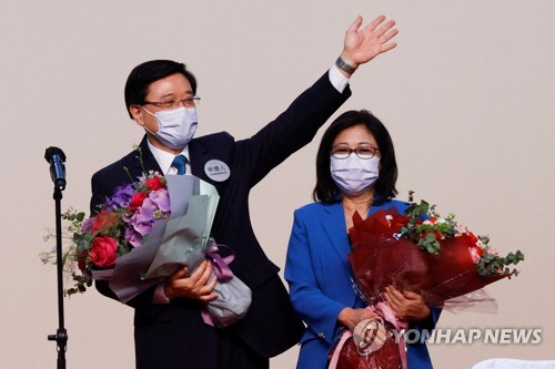 (로이터=연합뉴스) 8일 홍콩 행정장관 선거에서 당선된 존 리 전 정무부총리가 부인과 함께 단상에 올라 손을 흔드는 모습. 