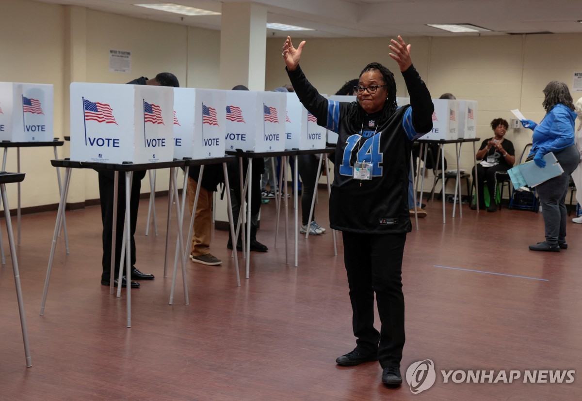 En esta fotografía publicada por Reuters, un trabajador electoral hace un gesto a los votantes que esperan para emitir su voto durante la votación anticipada de las elecciones presidenciales de Estados Unidos en un colegio electoral en Detroit, Michigan, el 3 de noviembre de 2024. (Yonhap)