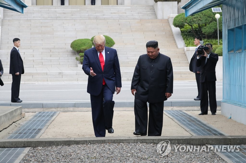 This photo, taken June 30, 2019, shows U.S. President Donald Trump (L) and North Korean leader Kim Jong-un crossing the Military Demarcation Line into the southern side of the border that separates the two Koreas. Trump became the first sitting U.S. president to set foot on North Korea, as he briefly crossed over to the communist state during his meeting with Kim. (Yonhap)