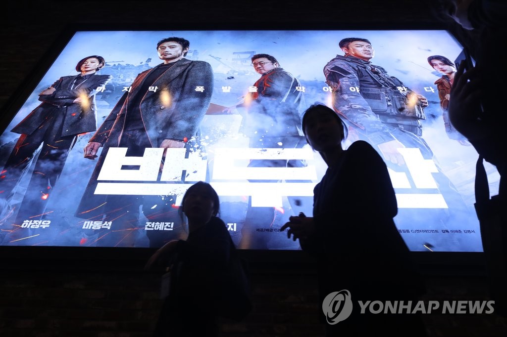 Moviegoers pass by a poster of the latest big-budget disaster movie, "Ashfall," at a theater in Seoul on Dec. 29, 2019. The previous day, the movie exceeded 5 million viewers in the 10 days since its release. (Yonhap)