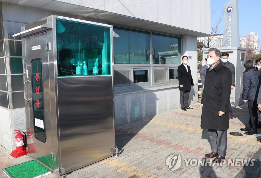 President Moon Jae-in, wearing a face mask, waits for disinfection measures in front of the National Human Resources Development Institute in Jincheon, North Chungcheong Province, on Feb. 9, 2020. (Yonhap)