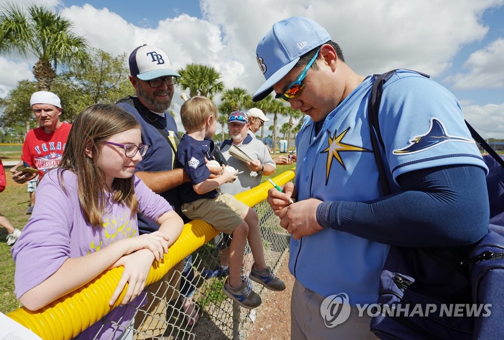 Choi Ji-man of the Tampa Bay Rays (R) signs a baseball for a fan after practice at Charlotte Sports Park in Port Charlotte, Florida, on Feb. 19, 2020. (Yonhap)