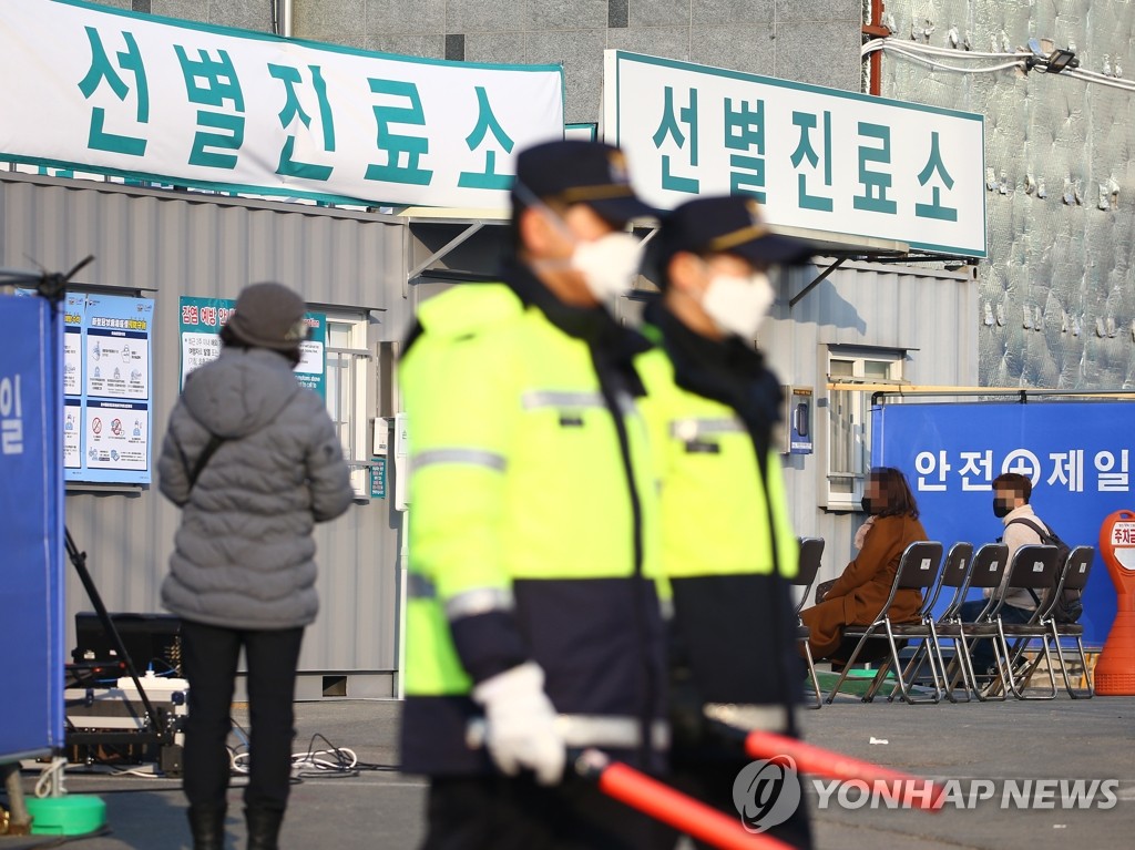 Police officers wearing masks stand guard at a medical center in Daegu, a city 300 kilometers southeast of Seoul, on Feb. 20, 2020, as people suspected of having been infected with the new coronavirus arrive to receive tests, with many patients confirmed to have been infected with the virus, named COVID-19, hospitalized in the center's negative pressure rooms. Twenty more confirmed cases came from the city and its adjacent North Gyeongsang Province the previous day. (Yonhap)