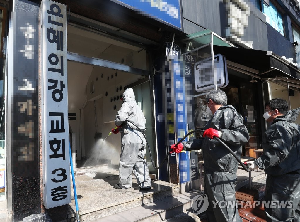Quarantine officials disinfect the entrance of the River of Grace Community Church in Seongnam, south of Seoul, on March 16, 2020. (Yonhap)