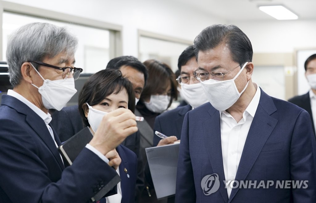3月25日，文在寅（左一）走访位于首尔市松坡区的新型冠状病毒诊断试剂生产企业。 韩联社