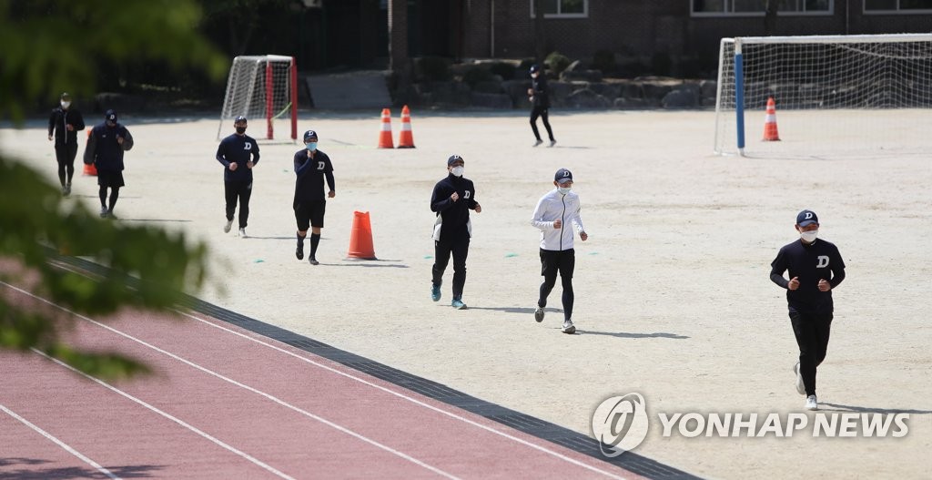 Students exercise in a schoolyard while wearing masks at a high school in Daegu, 300 kilometers south of Seoul, on April 28, 2020. (Yonhap)