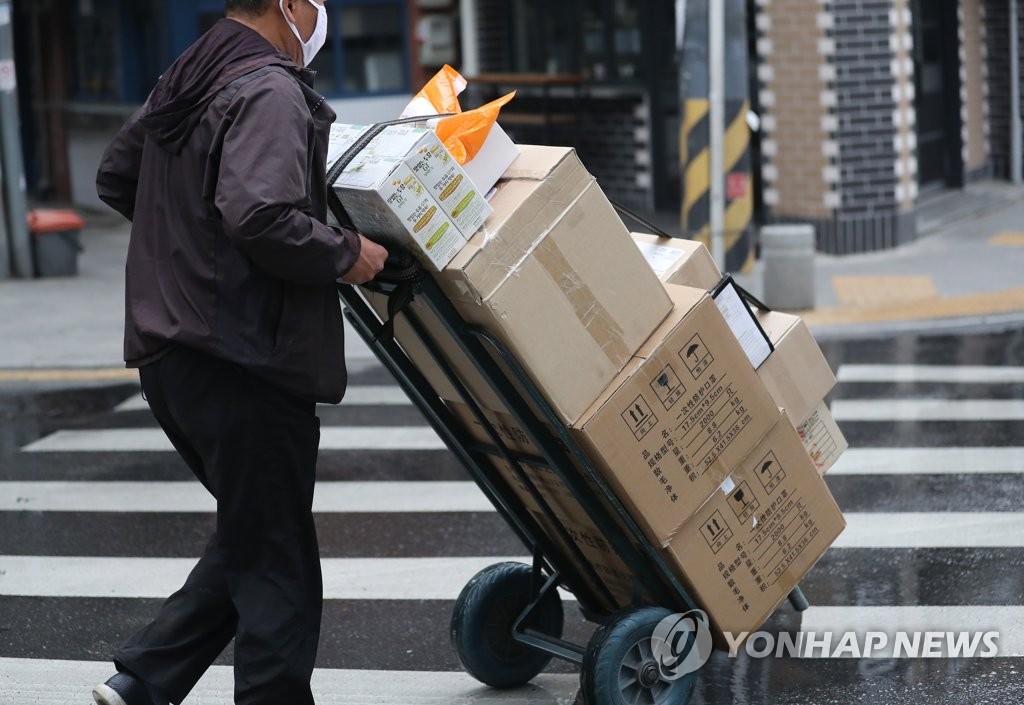 A deliveryman moves boxes in Jongno, central Seoul, on May 1, 2020. (Yonhap)