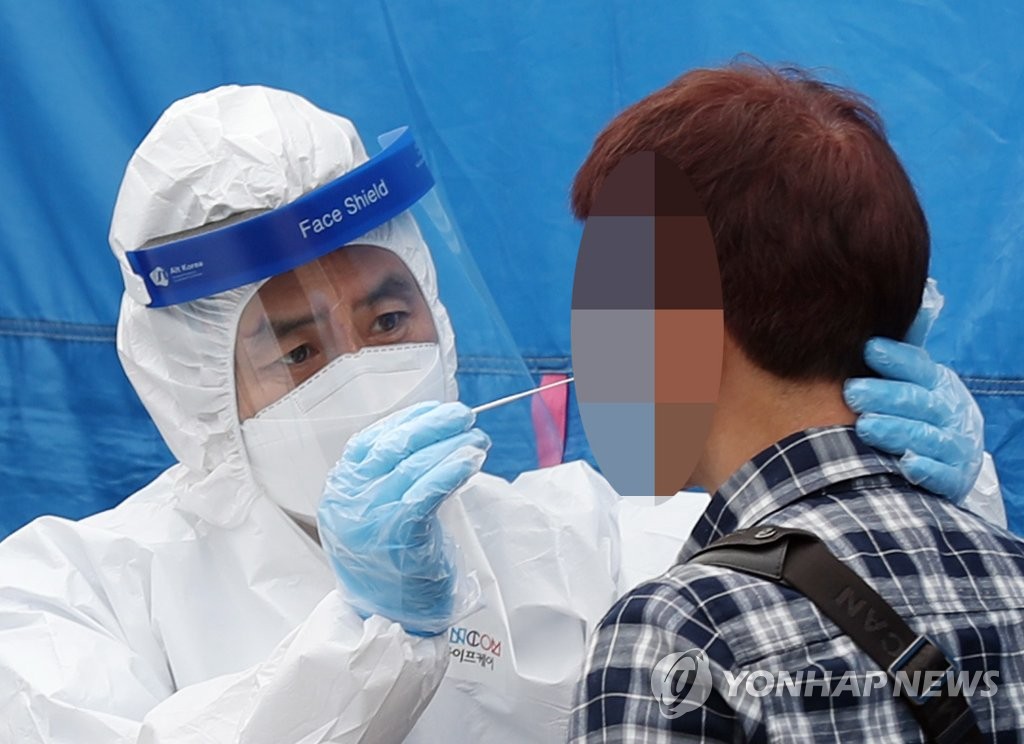 A medical staff carries out a new coronavirus test on a visitor at a makeshift COVID-19 clinic located in Bucheon, just west of Seoul, on May 27, 2020. (Yonhap)