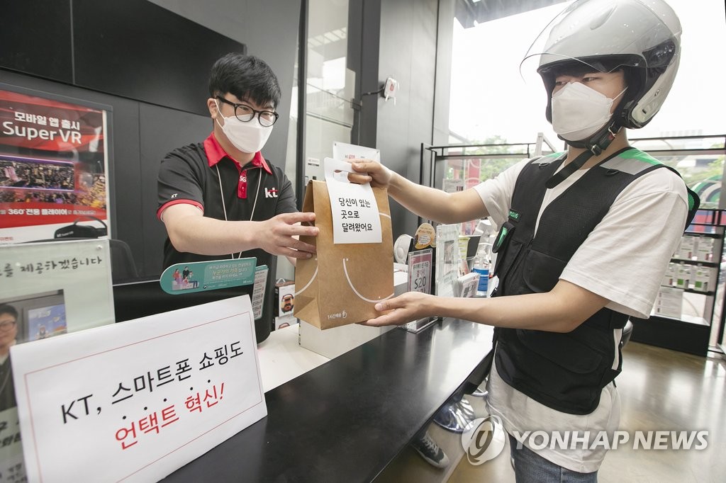 A KT Corp. worker hands a package to a Mesh Korea Co. delivery driver as part of the carrier's phone delivery service in this photo provided by KT on July 1, 2020. (PHOTO NOT FOR SALE) (Yonhap)