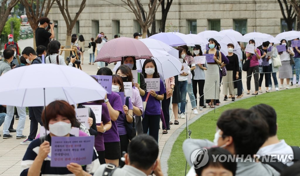 Participants, dressed in purple and holding violet-colored umbrellas, walk in front of Seoul City Hall in central Seoul on July 28, 2020, as they march to the National Human Rights Commission of Korea, demanding a "proper investigation" into sexual misconduct allegations raised against late Seoul Mayor Park Won-soon. (Yonhap)
