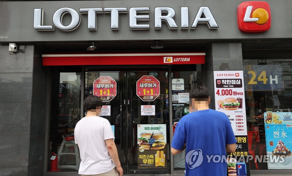 Pedestrians stand in front of a Lotteria franchise in the eastern Seoul ward of Gwangjin, which was temporarily closed on Aug. 12, 2020, due to new coronavirus concerns. (Yonhap)