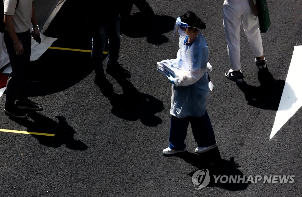 A medical worker guides visitors at a clinic in central Seoul on Aug. 25, 2020. (Yonhap)
