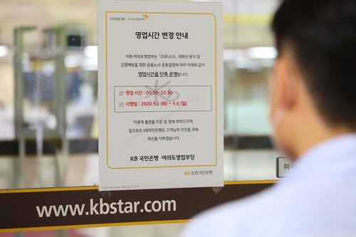 A visitor looks at a notice informing customers of the shortening of business hours by one hour at a KB Kookmin Bank branch in Seoul on Sept. 1, 2020. The step was taken at banks in Seoul and its satellite cities to prevent the spread of COVID-19. The operation hours are from 9:30 a.m. to 3:30 p.m. (Yonhap)