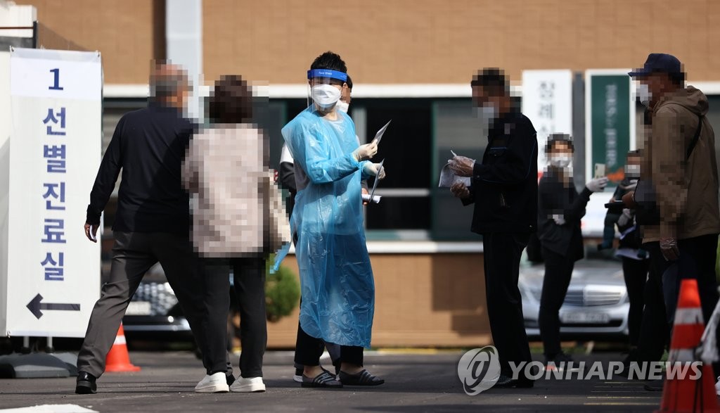 Visitors wait to receive new coronavirus tests at a makeshift clinic in central Seoul on Oct. 11, 2020. (Yonhap)