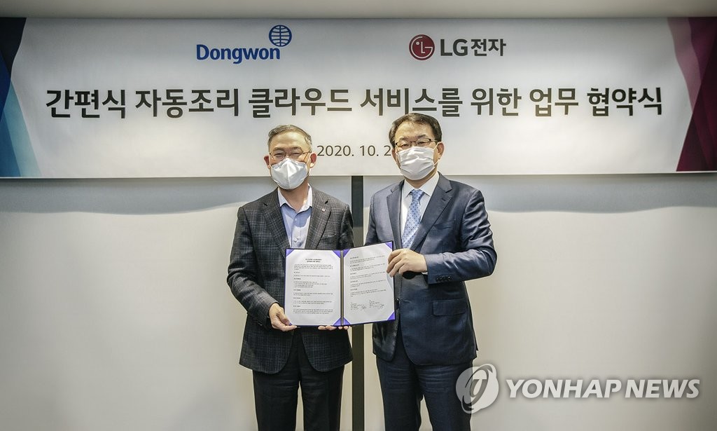 This photo provided by LG Electronics Inc. on Oct. 30, 2020, shows Kim Jae-ok (R), the CEO of Dongwon F&B Co., and Song Dae-hyun, who leads the home appliance and air solutions unit at LG Electronics, posing for the camera after signing a partnership in Seoul. (Yonhap)